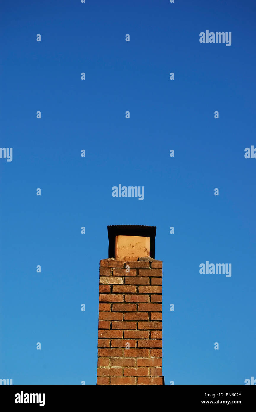 Isolated top of a chimney against blue sky. Stock Photo