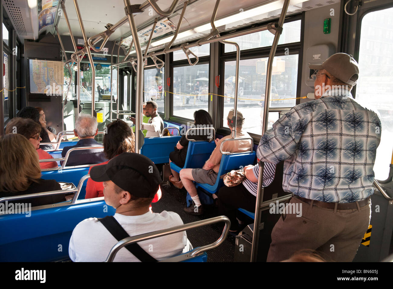 interior of late model New York Transit Authority New York City bus with seated & standing passengers Stock Photo