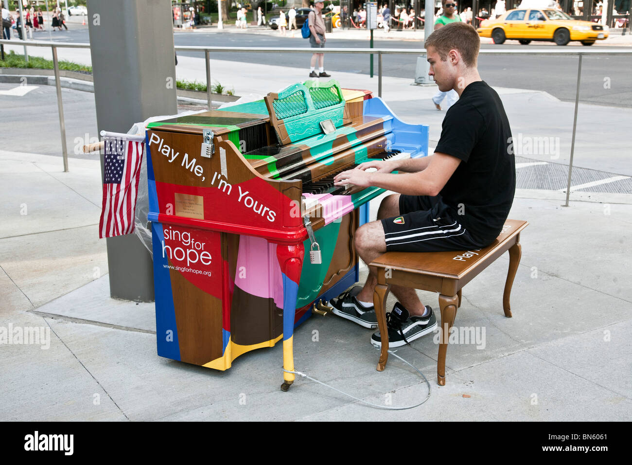 intent young man plays gaily decorated Sing for Hope public piano placed near the entrance to Lincoln Center in New York City Stock Photo