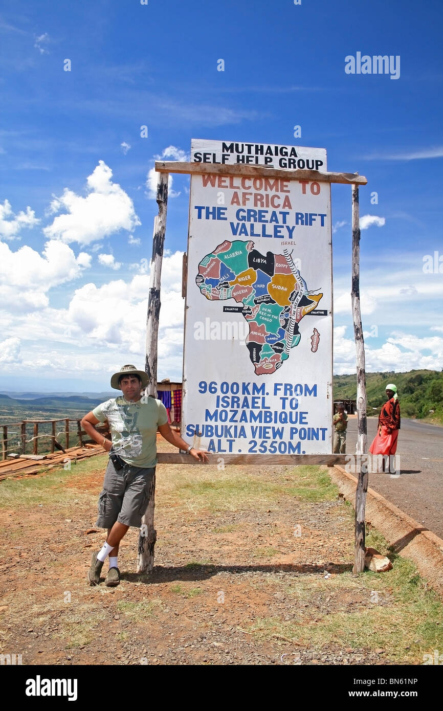 A tourist posing near the signboard of 'The Great Rift Valley' on a highway leading to Lake Nakuru in Kenya, East Africa. Stock Photo