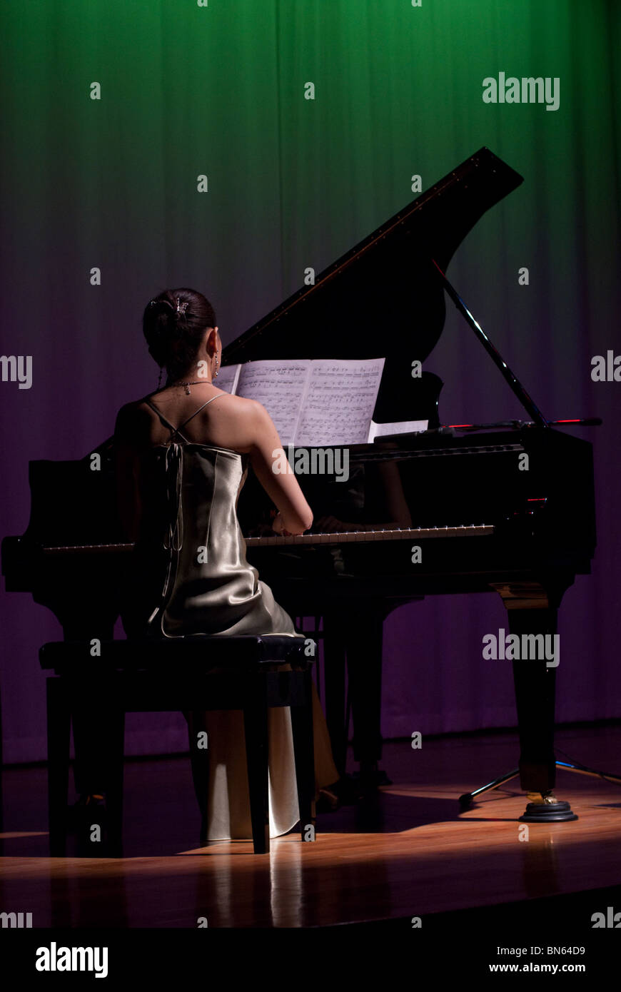 A young woman in evening dress plays a grand piano onboard the Kiso Ferry enroute to Hokkaido. Stock Photo