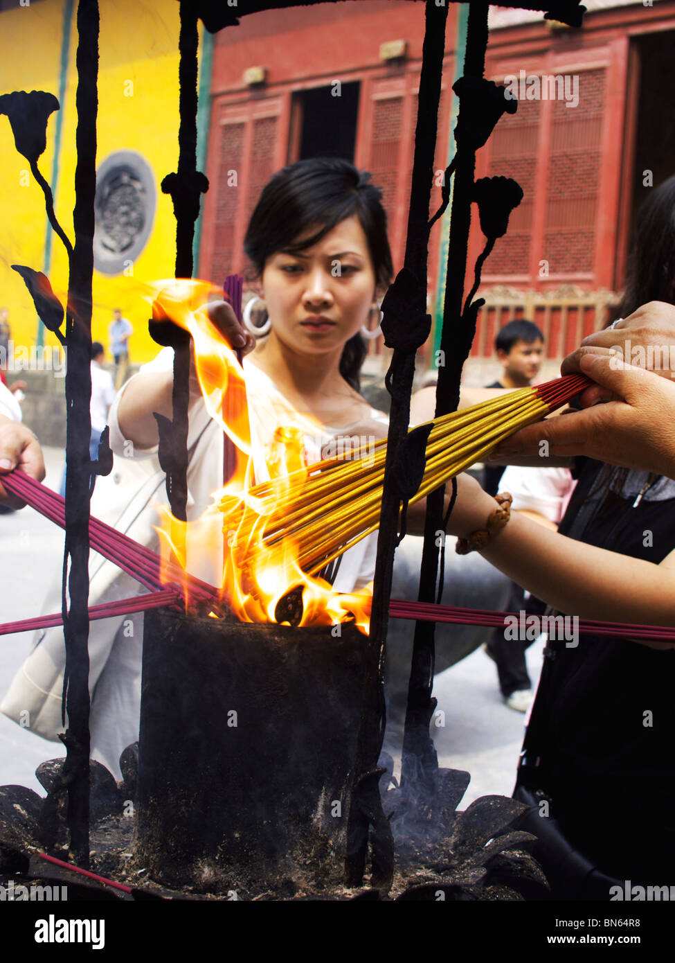 Young Chinese woman lights incense sticks at Lingyin Temple in Hangzhou Stock Photo