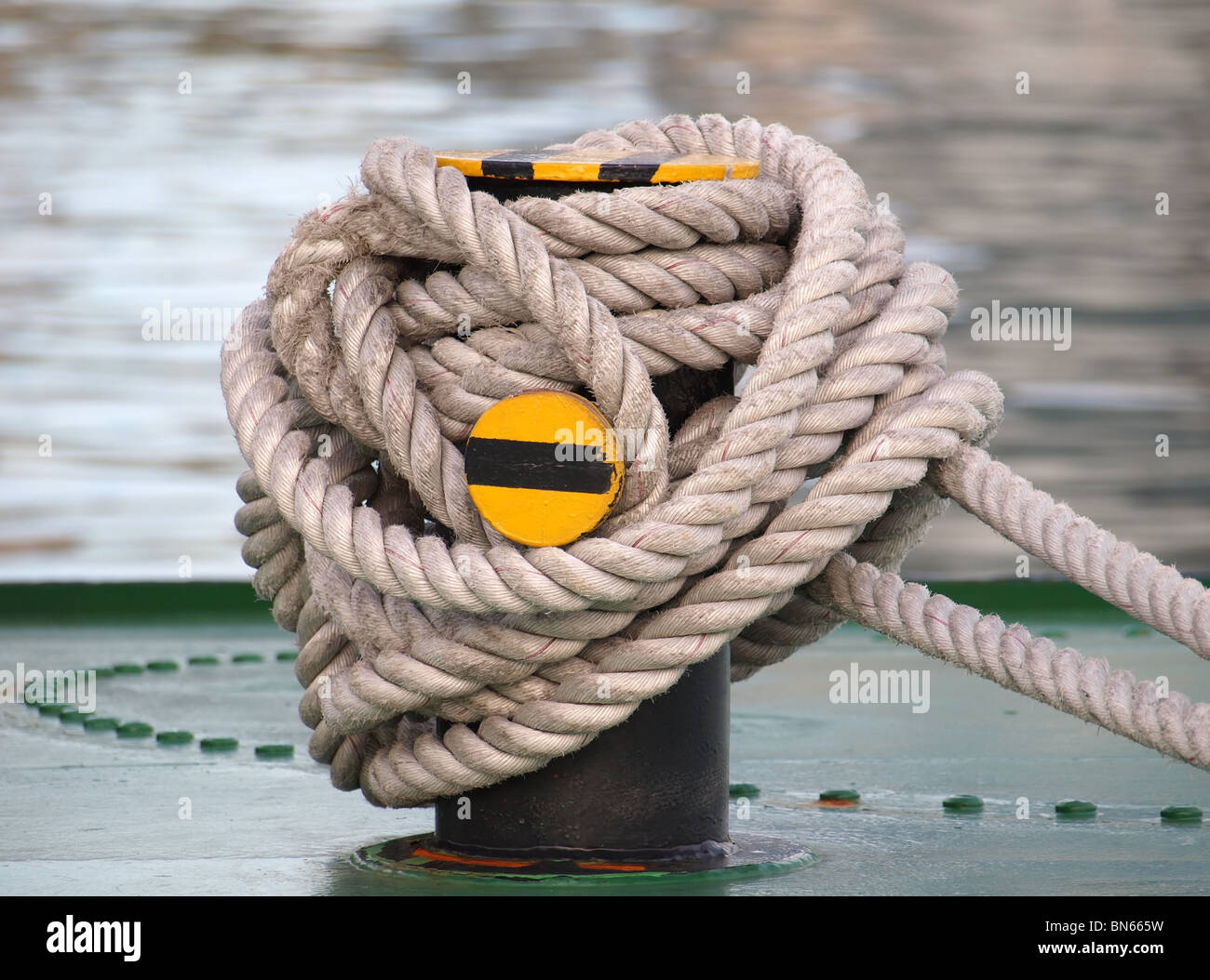 A thick rope is wrapped around a strong post on deck of a ship