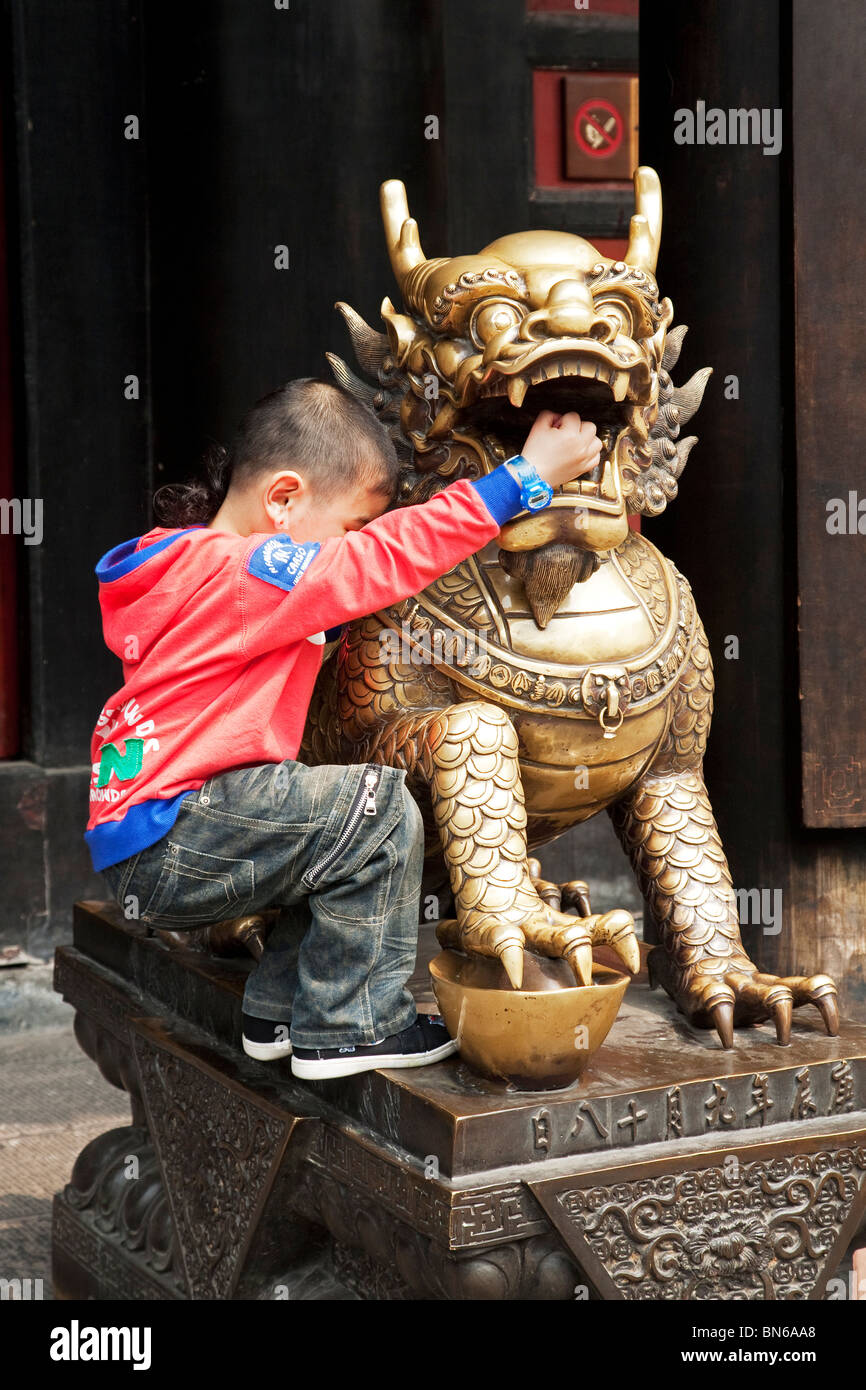Child playing on the Golden dragon statue at (Buddhist) Wenshu Temple in Chengdu, China. Stock Photo