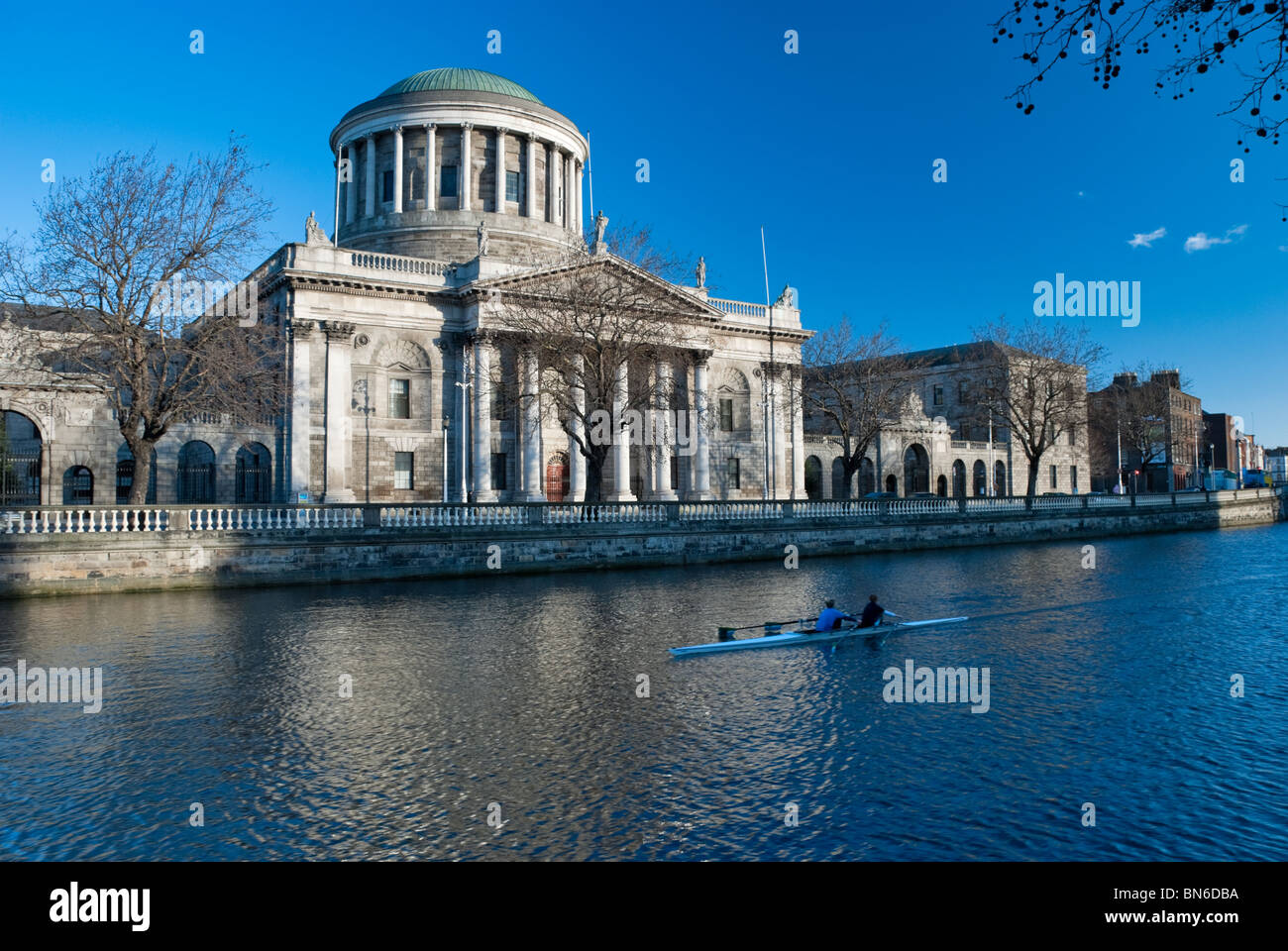 Early morning rowers passing by the Four Courts, the location of the Supreme and High Court of Ireland. Stock Photo