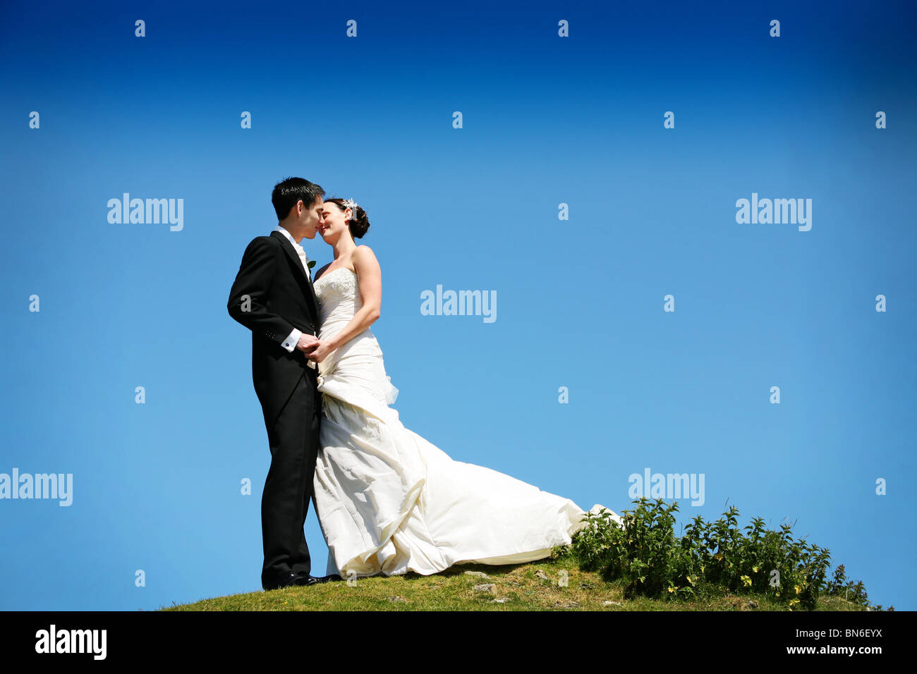 Romantic Bride and Groom kissing on their wedding day stood on top of a ...