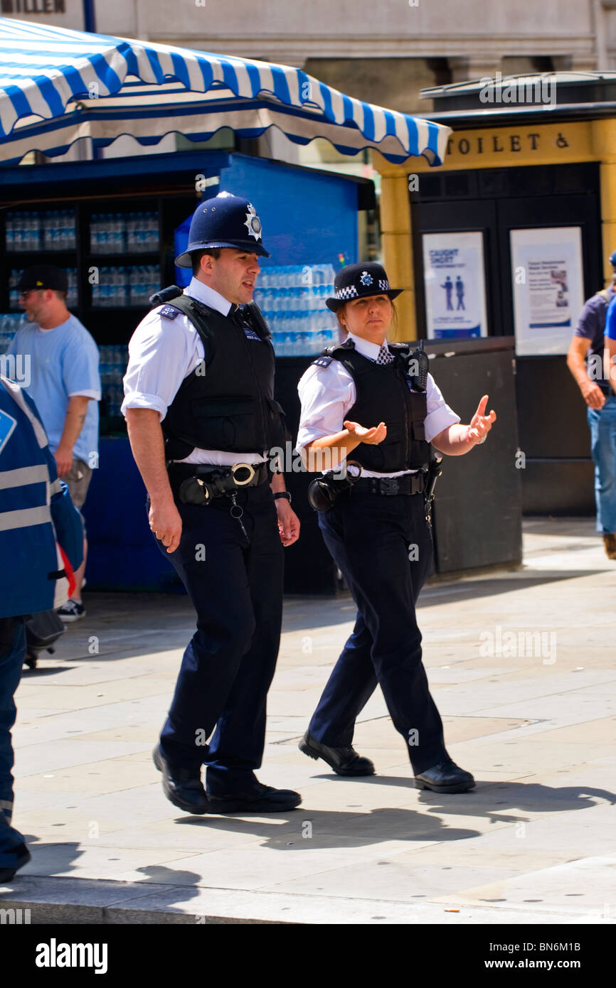 London Gay Pride , policeman with policewoman in uniform on patrol walking & chatting Stock Photo