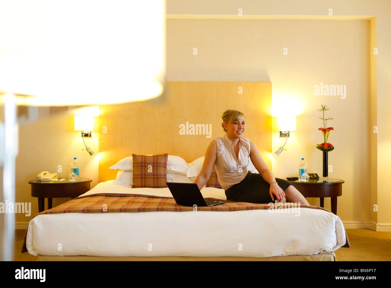 Woman working on a laptop in a hotel room, whilst on a business trip. Stock Photo