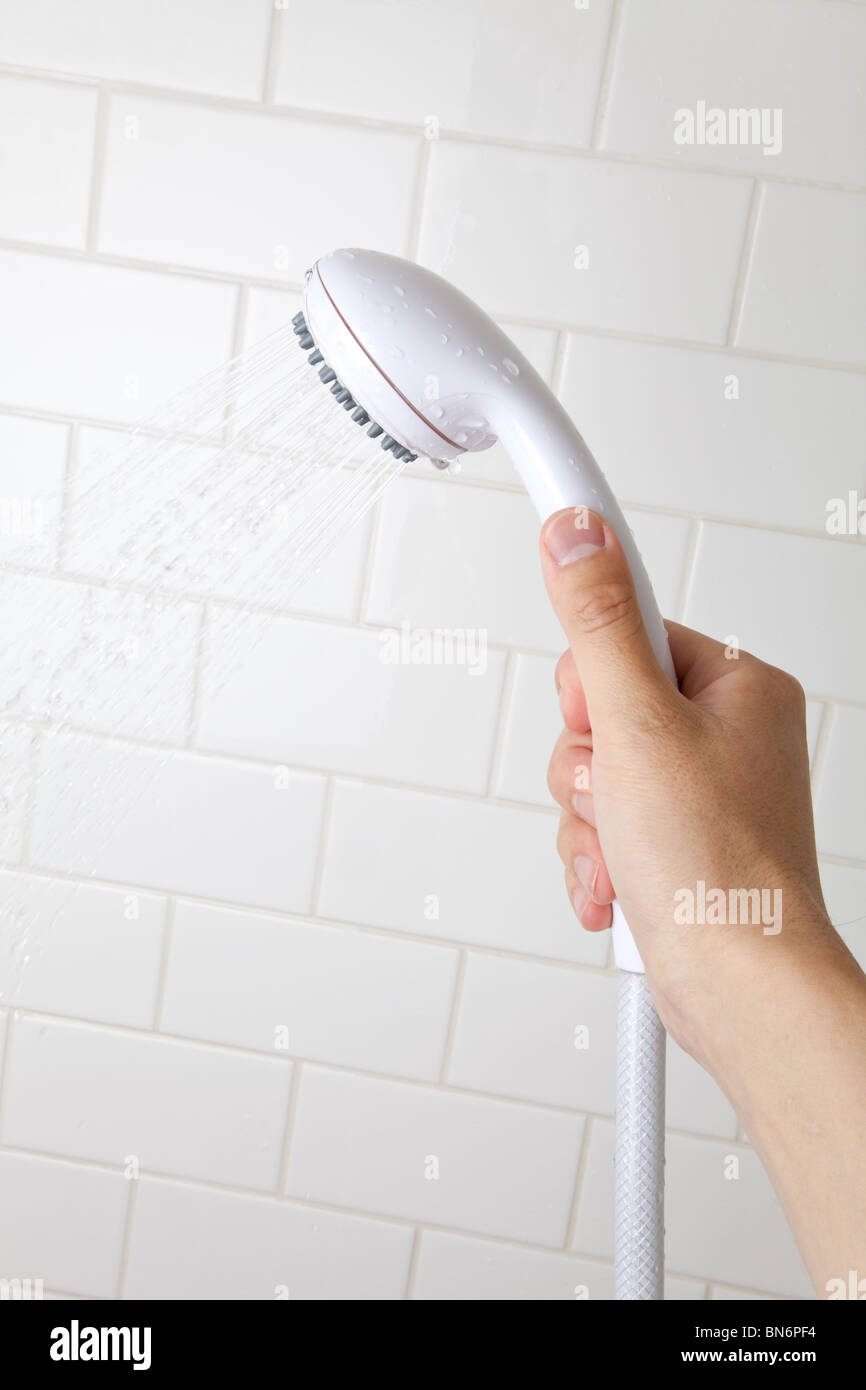 Hand holding a Shower Head Flowing Spraying Water Stock Photo