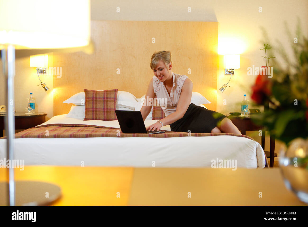 Woman in hotel suite, sat on a bed. Stock Photo