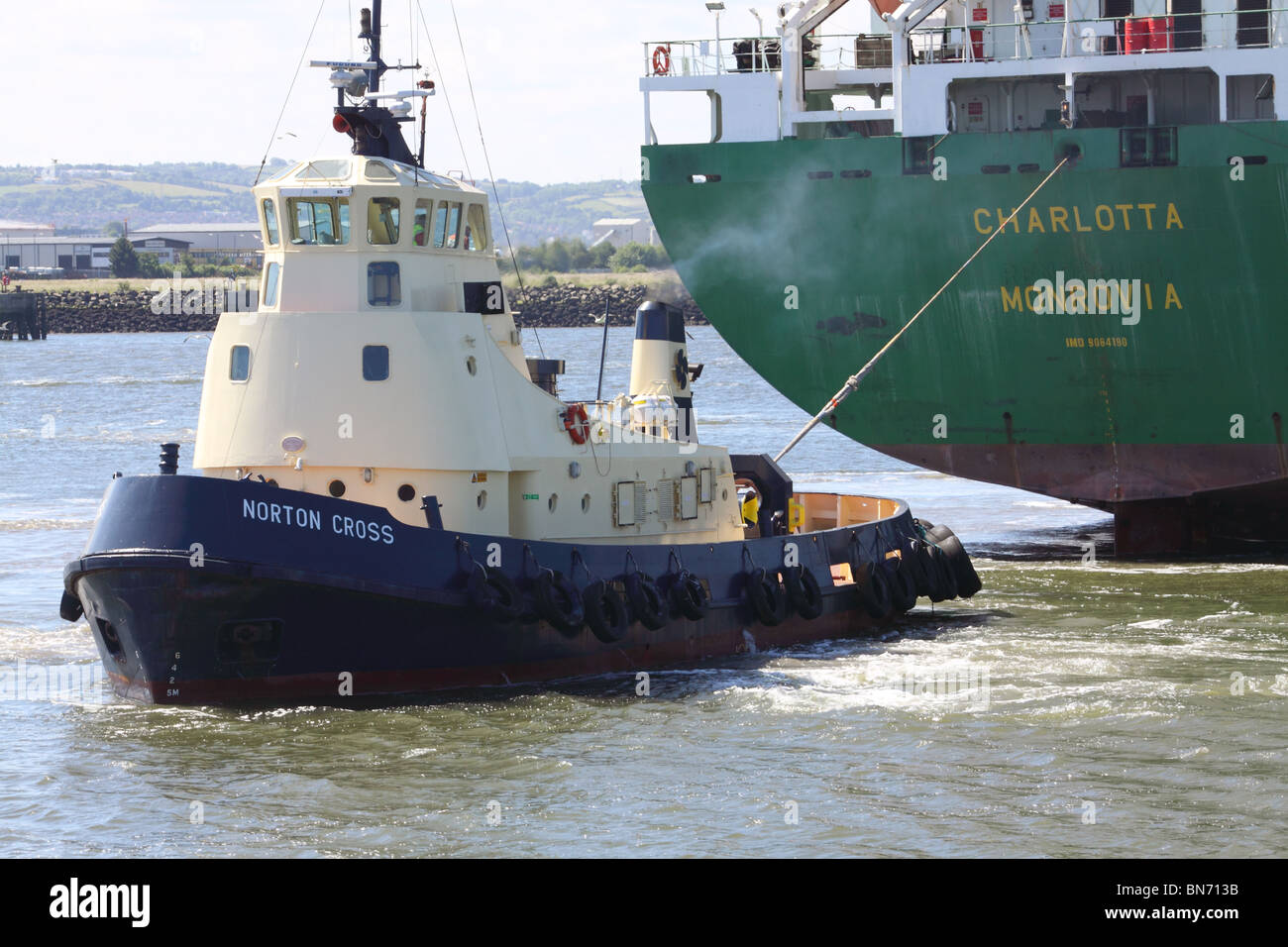 tugboat manouvering a container ship in Belfast docks Stock Photo