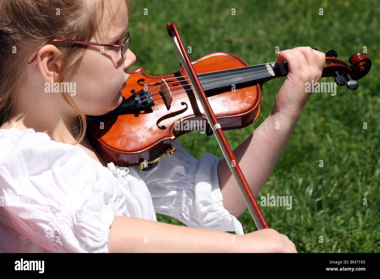 A young girl in a white dress playing her violin Stock Photo - Alamy