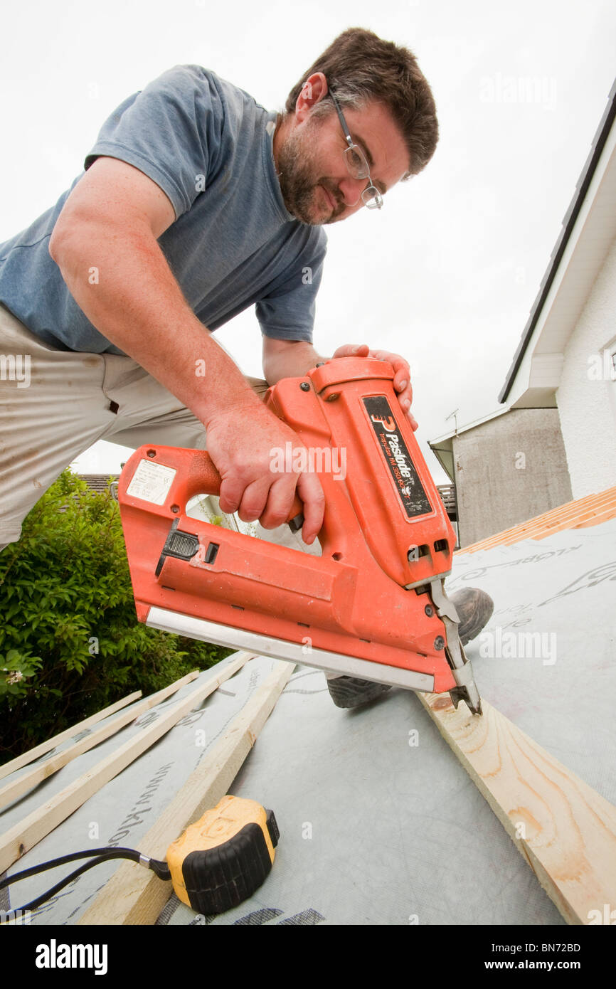 A builder using a nail gun Stock Photo Alamy