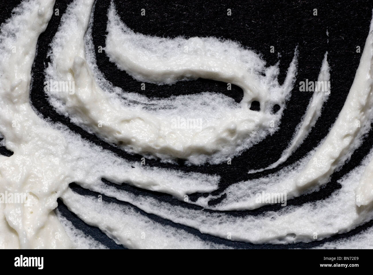 A spooky image of a ghost flying through the air is made with white buttercream icing on a black foam board. Stock Photo