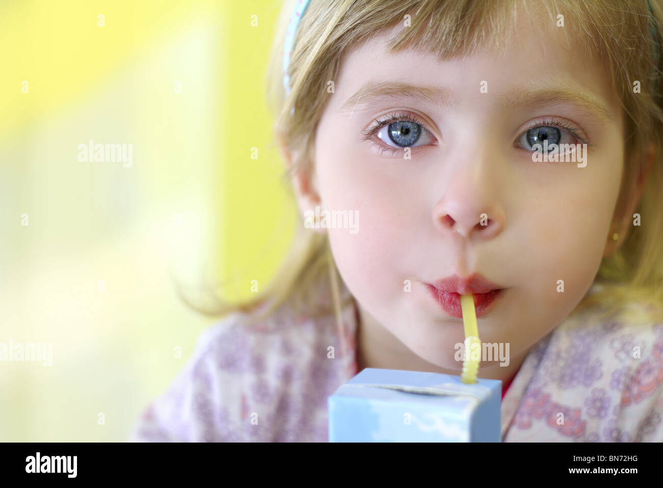 blond little girl drinking straw tetra brick blue eyes Stock Photo