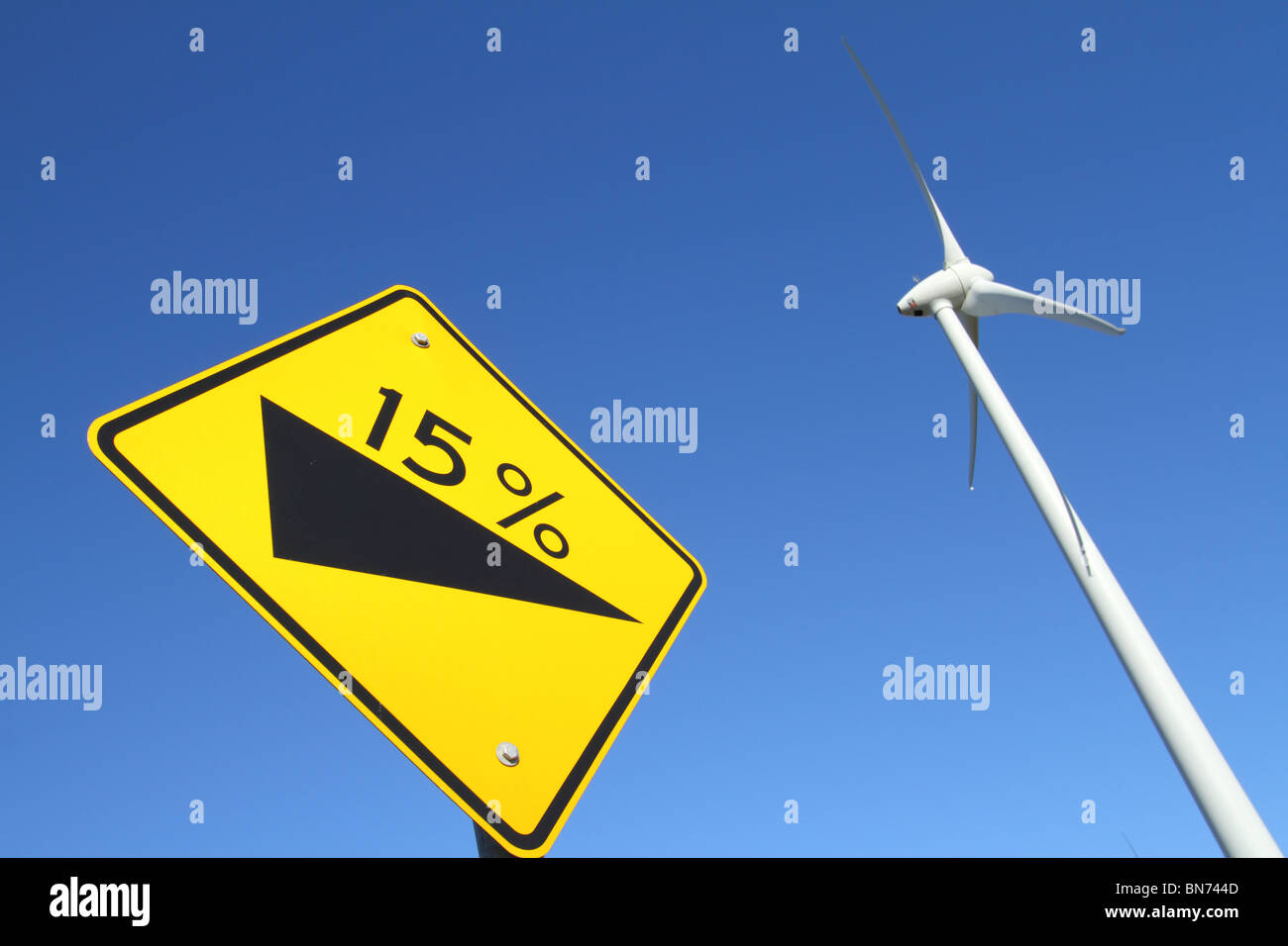 A single wind energy converter and a single signpost photographed next to each other with a blue sky Stock Photo