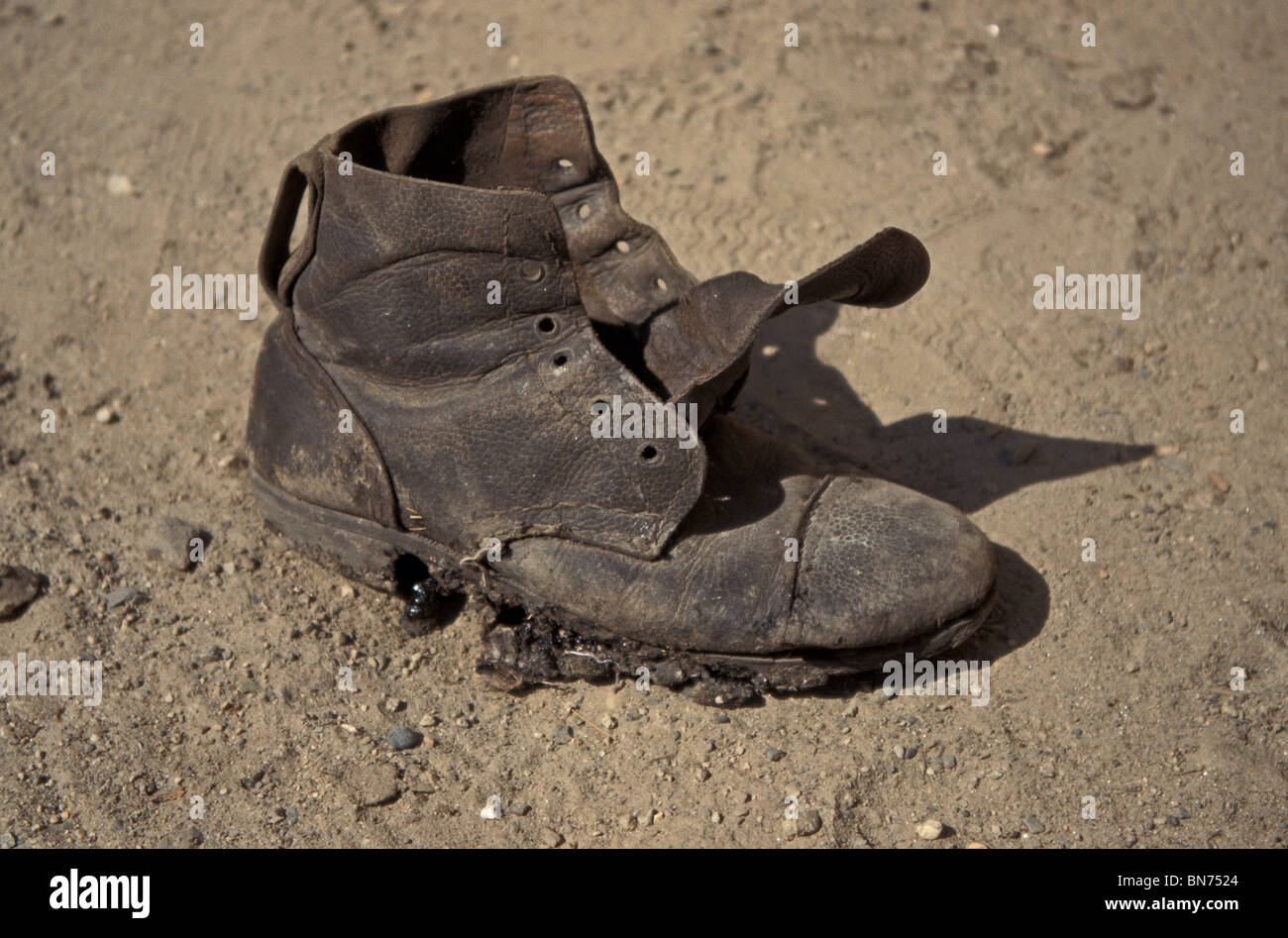 Old Boot – Worn out boot in dried up river bed. Stock Photo