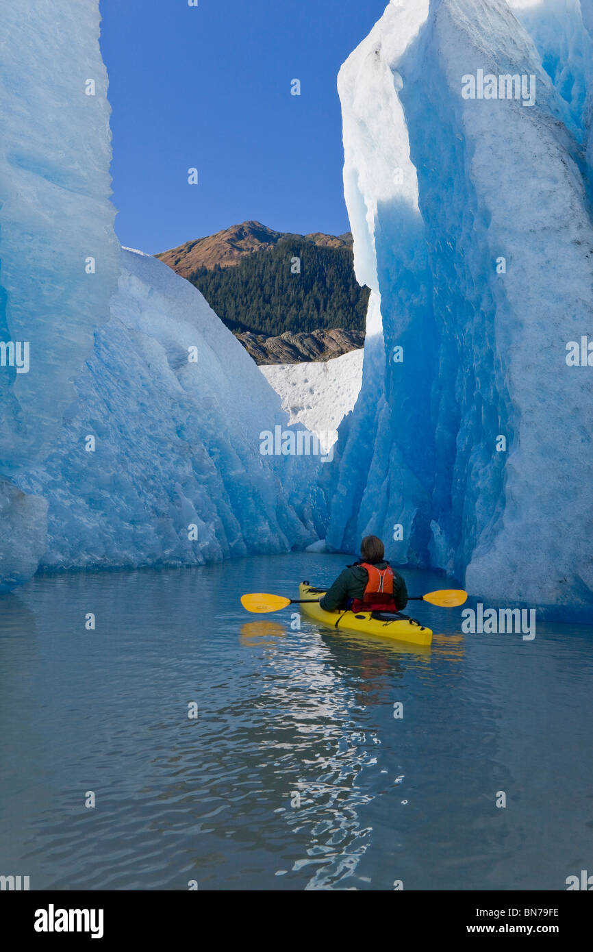 A kayaker paddles and explores the seracs of Mendenhall Glacier, Autumn morning, Mt. McGinnis in the background, Alaska Stock Photo