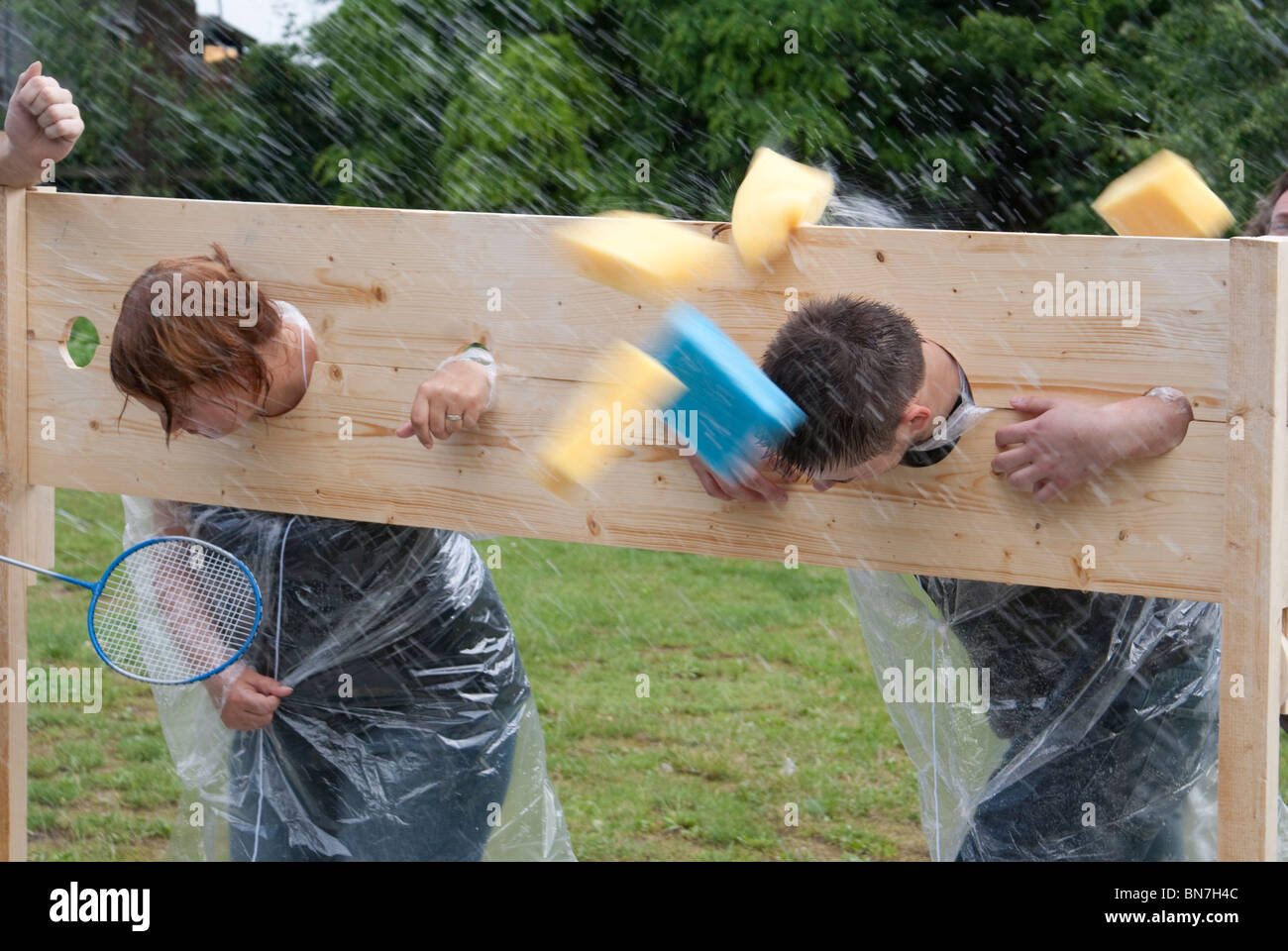 Throwing sponges at people in stocks as team building exercise Stock Photo