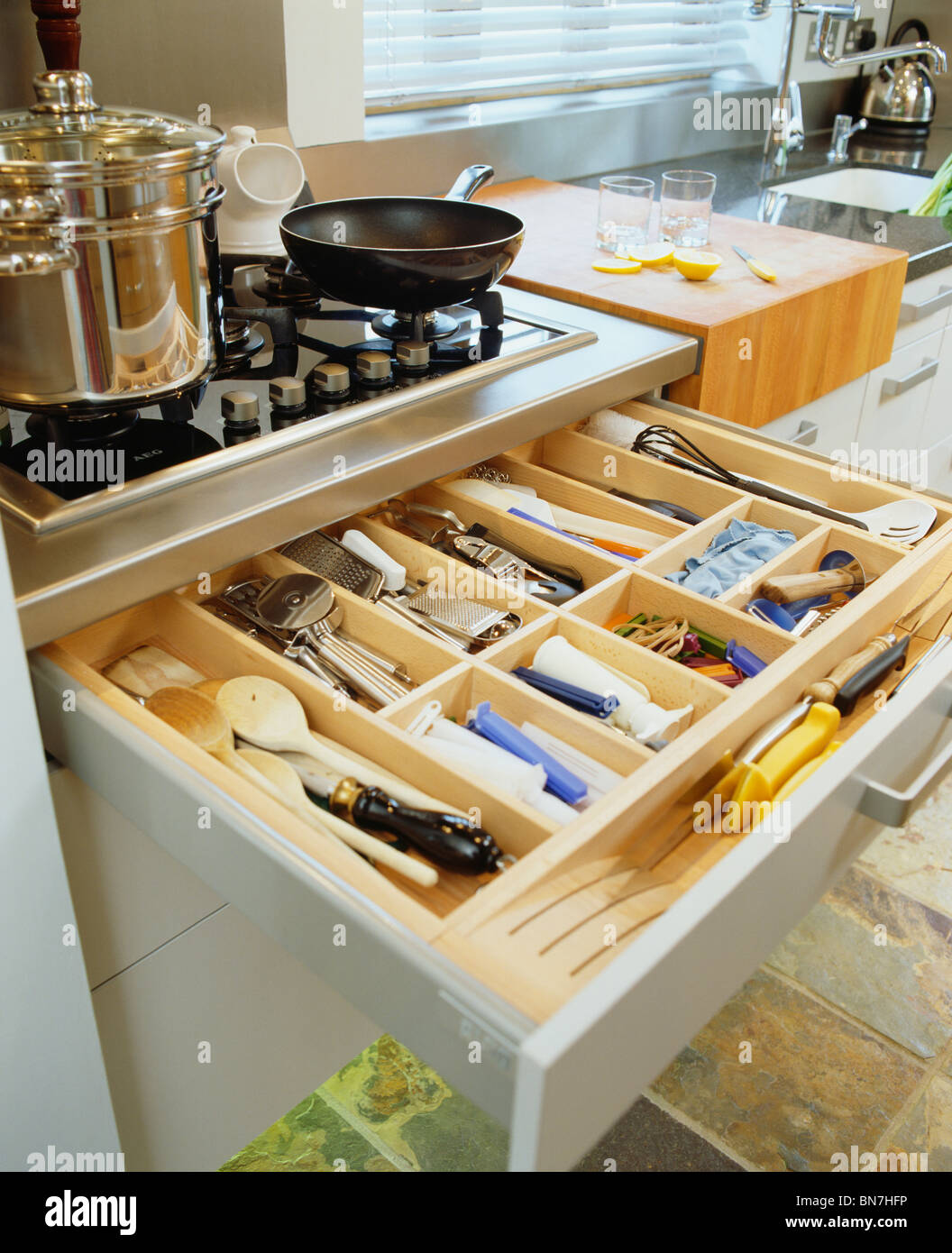 Close Up Of Open Cutlery Storage Drawer Below Pans On Kitchen Hob