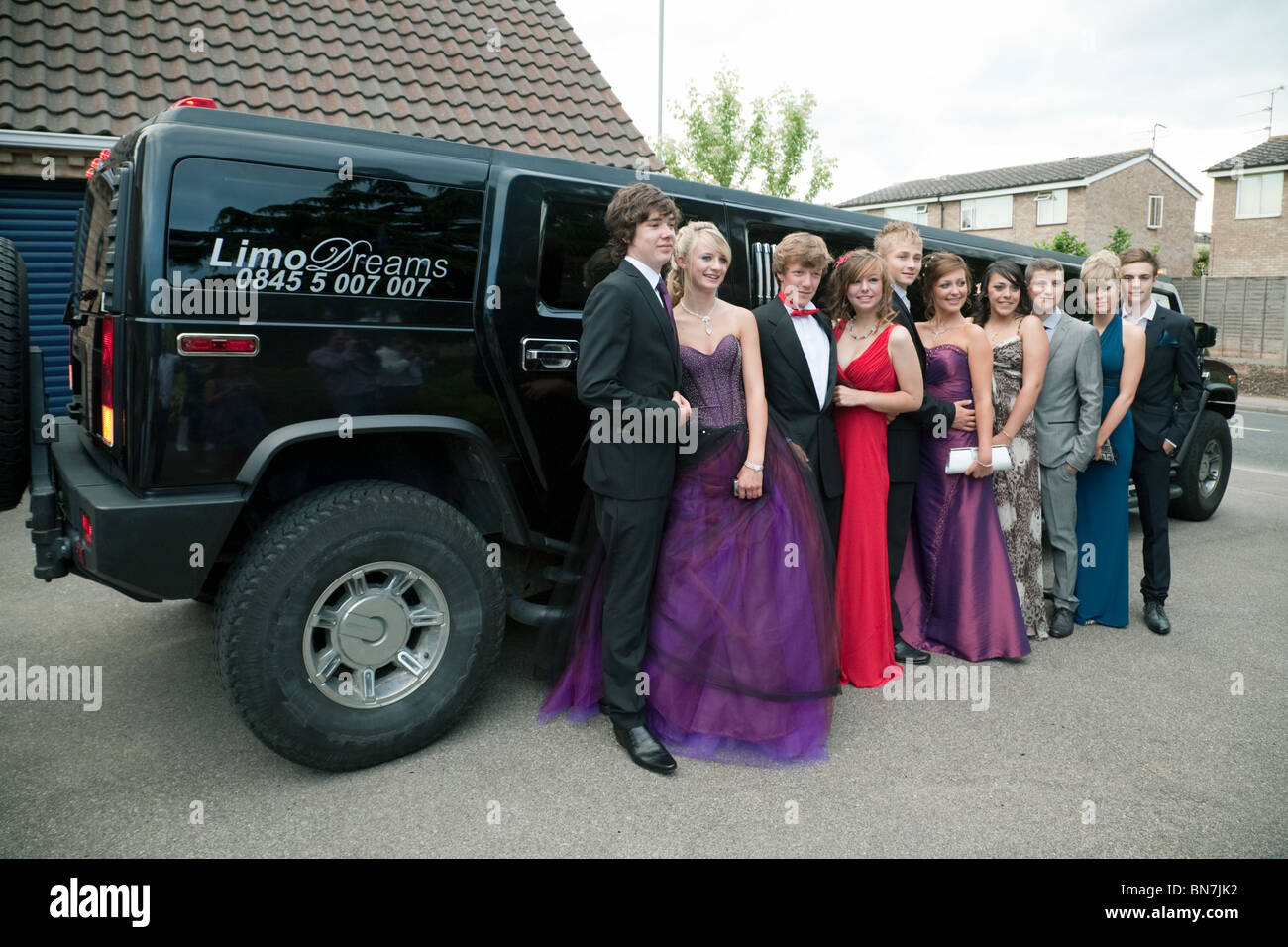 A group of teenage couples dressed up ready for their school prom pose in front of their limo, Cambridgeshire, UK Stock Photo