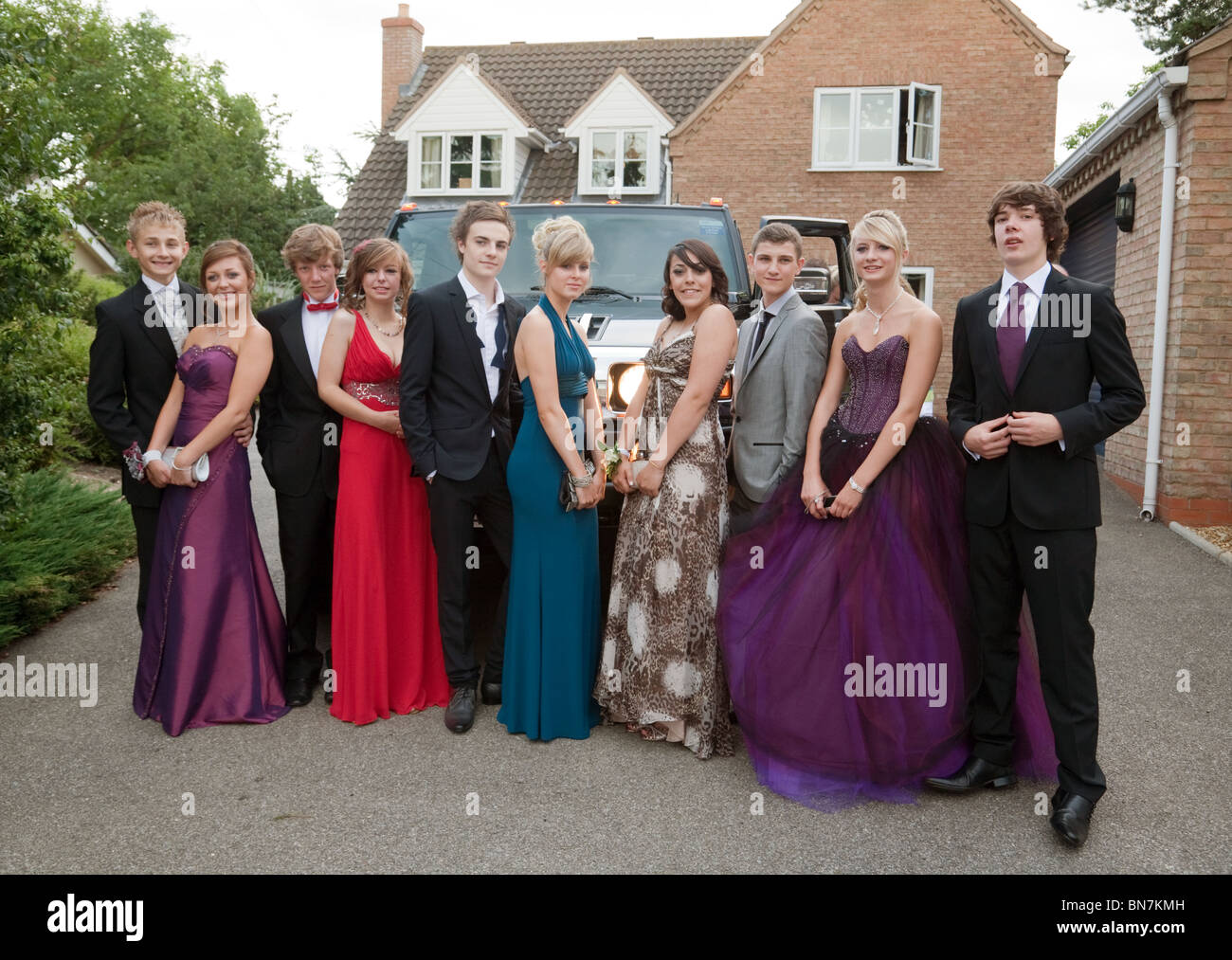 Teenage girls and boys dressed up ready for their school prom pose in front of their limo, Cambridgeshire, UK Stock Photo