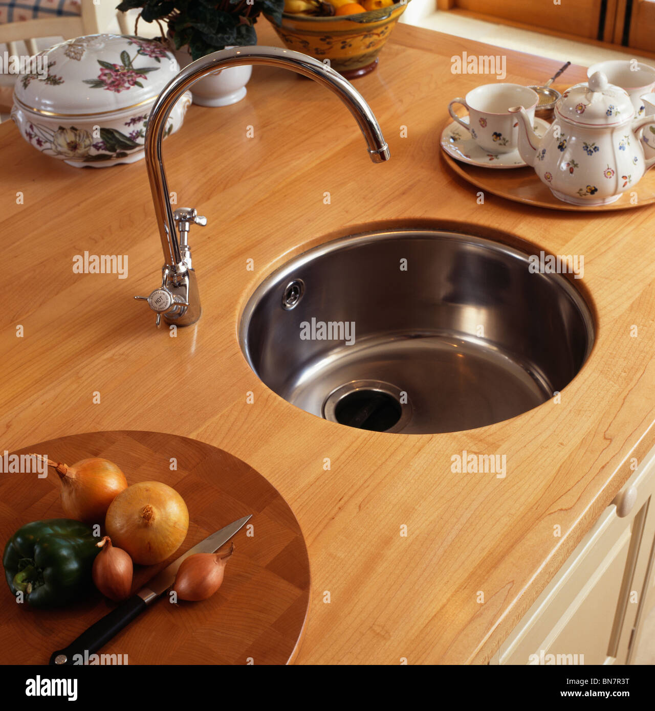 Close-up of circular stainless- steel under-set basin and mixer tap in wood worktop Stock Photo