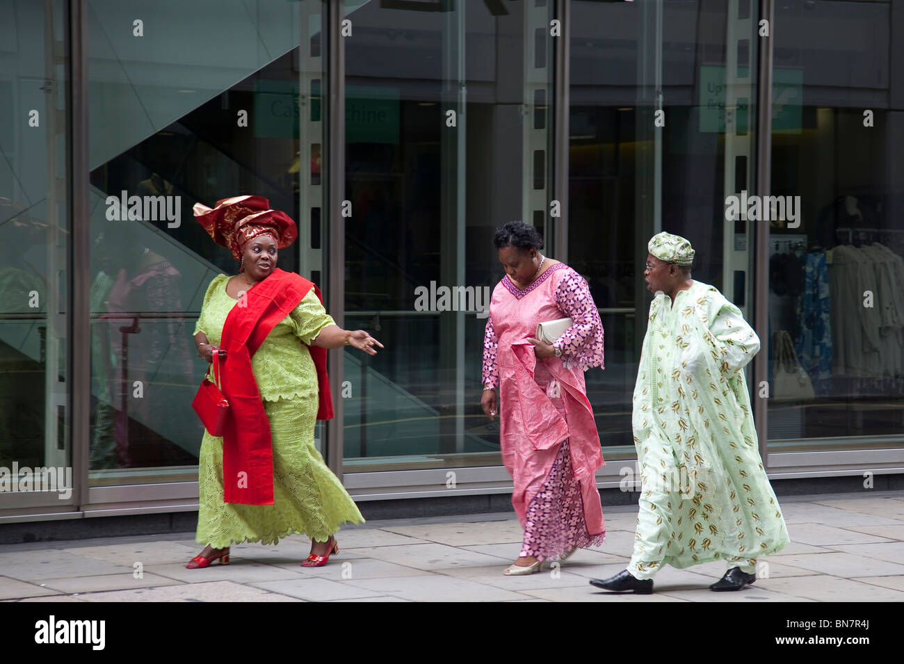 A man and two women of African origin in colourful robes in the streets of London Stock Photo
