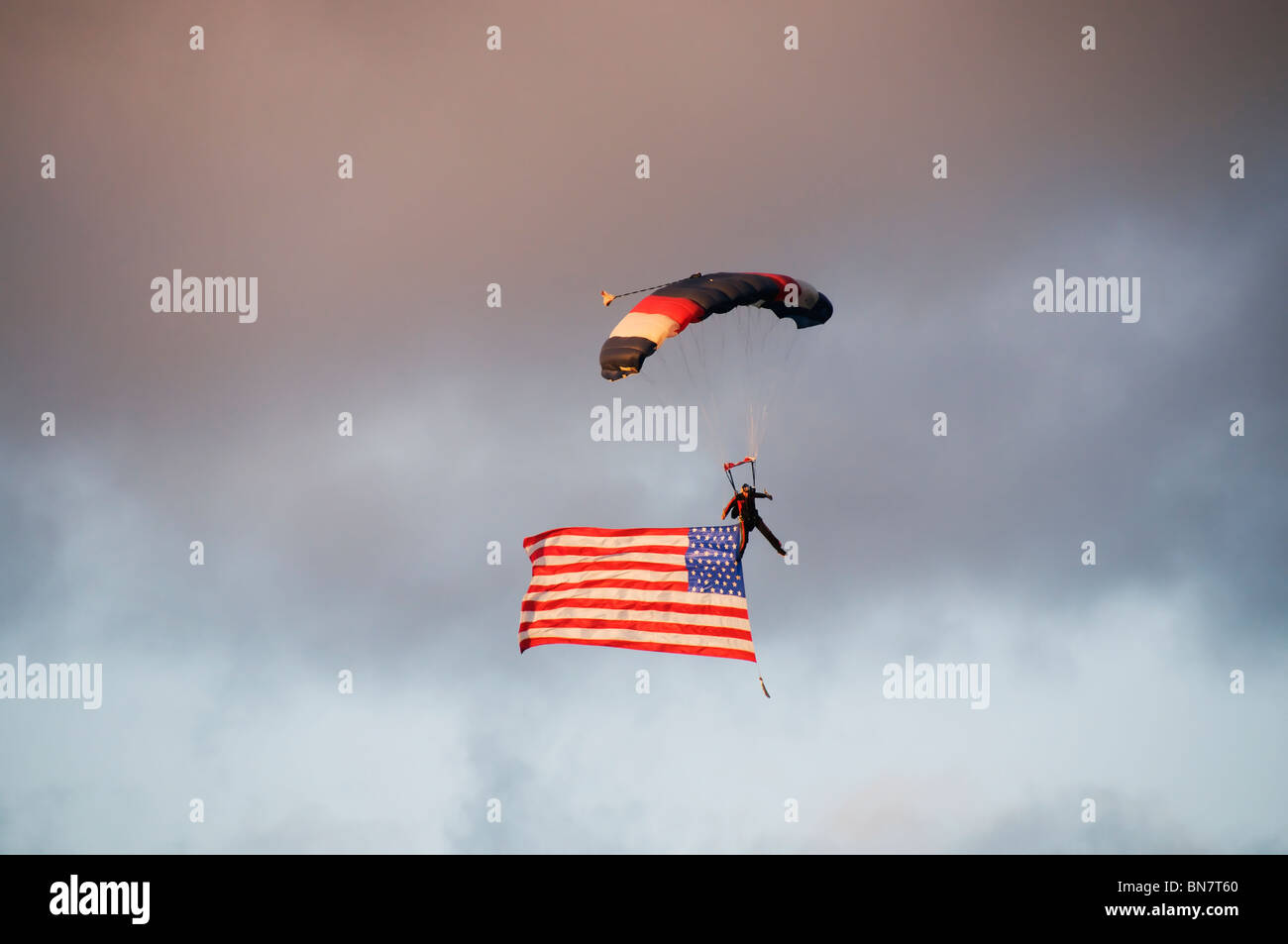 A skydiver with an American flag soars through the air over the excited crowd at the Artesian Family Festival in Tumwater, WA. Stock Photo