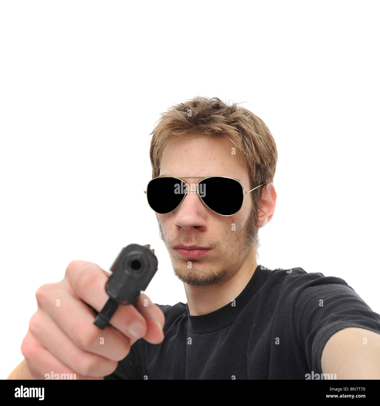 A young adult holds the viewer at gunpoint. Isolated on white background. Stock Photo