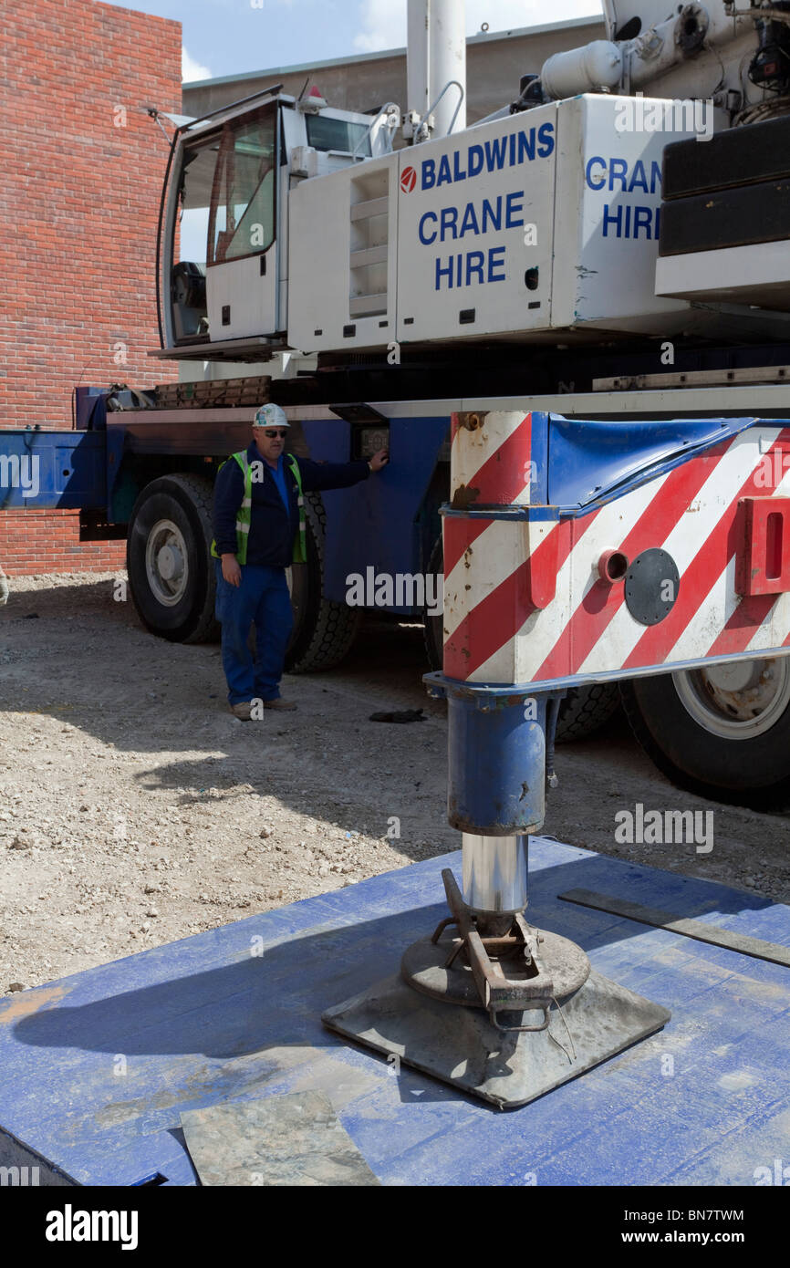 Setting up outriggers for a tall mobile crane on a construction site