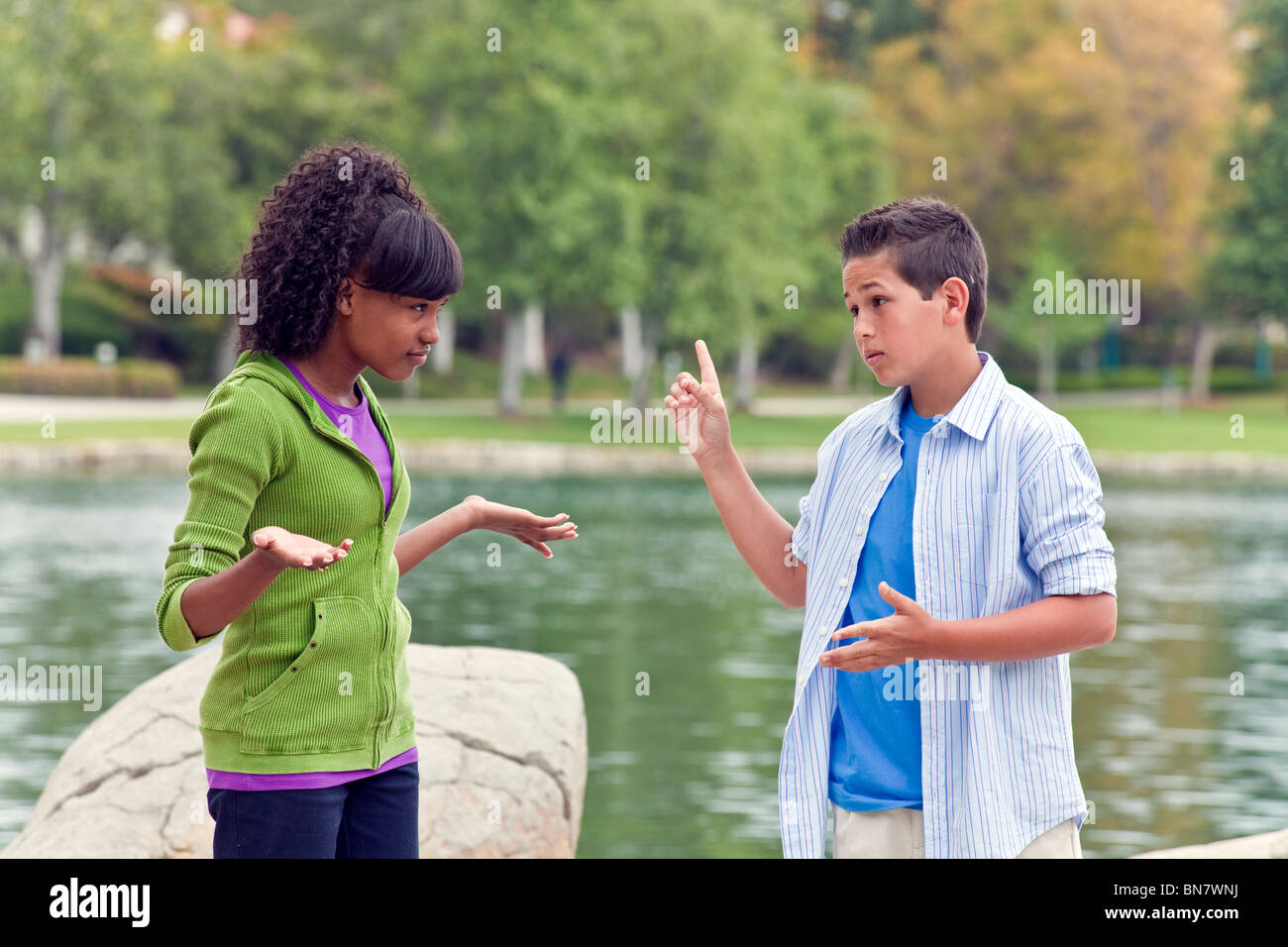 Teens hanging out Ethnically diverse multiracial teenage African American Girl and Caucasian boy talking practice for debate team hand gesturing. MR Stock Photo