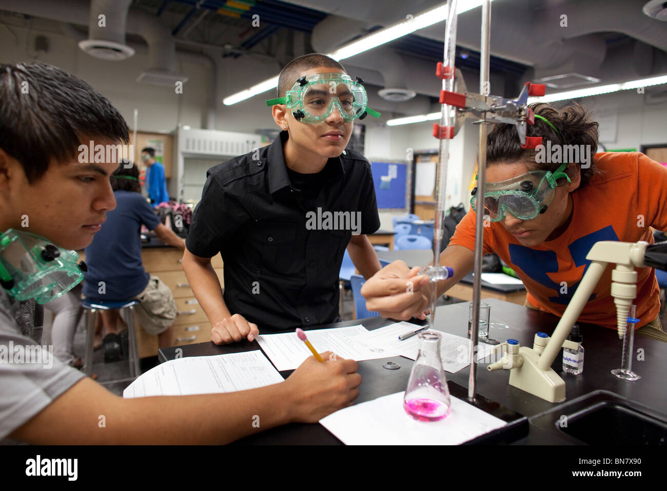 Students in safety goggles do an experiment in chemistry class at the Math, Engineering, Technology and Science Academy (METSA) Stock Photo