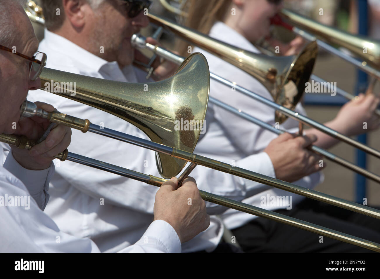 men playing trombones in a traditional brass band outdoors in the uk
