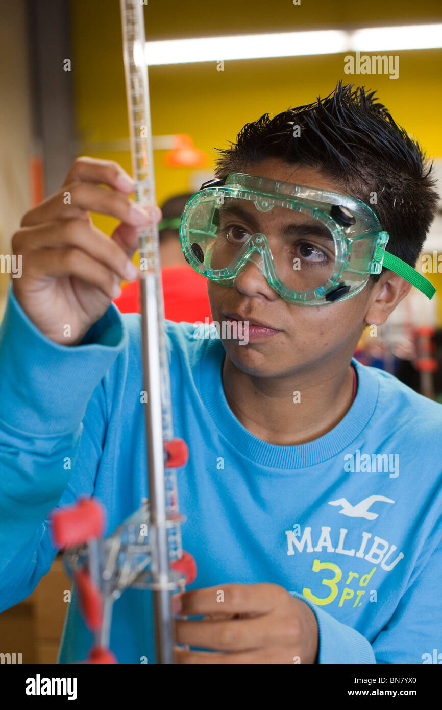Male high school student wearing safety goggles performs a titration