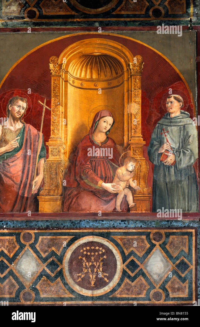 15th-century painting of the Umbrian school, The Madonna of Mercy between St Francis and St John the Baptist. Stock Photo