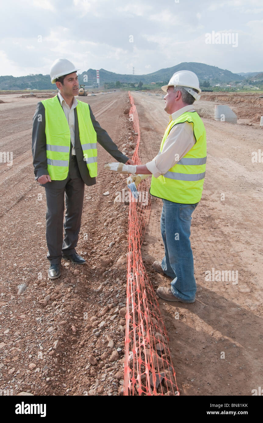 Hispanic businessman and construction worker standing in field Stock Photo