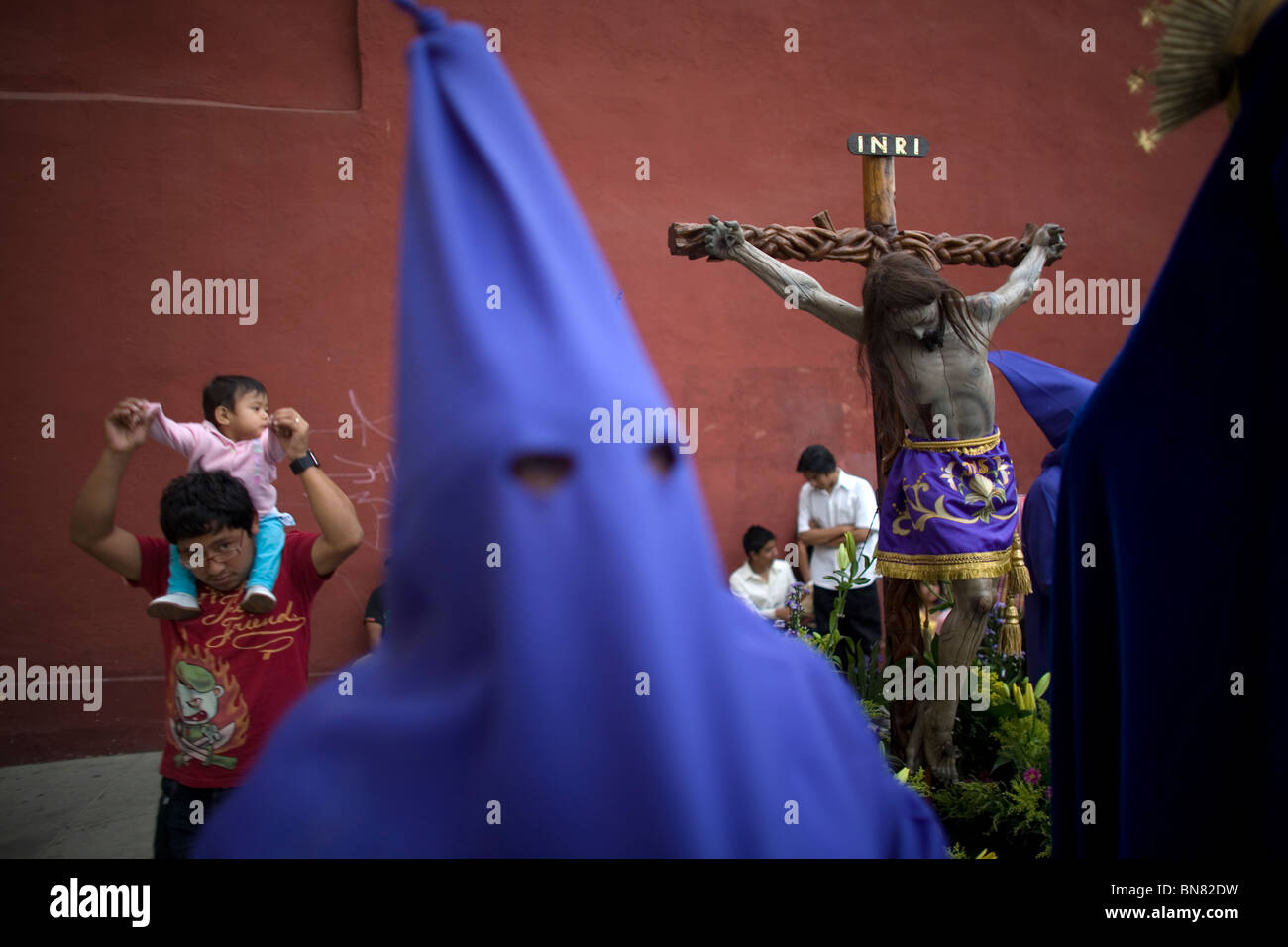 A penitent wearing a pointed hat escorts a crucified Jesus Christ statue during holy week