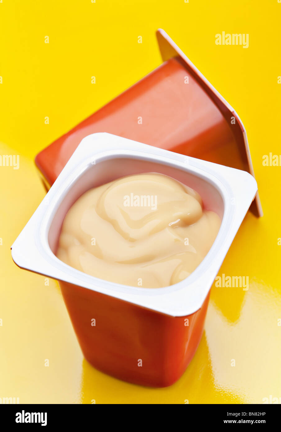 Cream caramel yoghurt in plastic box on yellow Stock Photo - Alamy