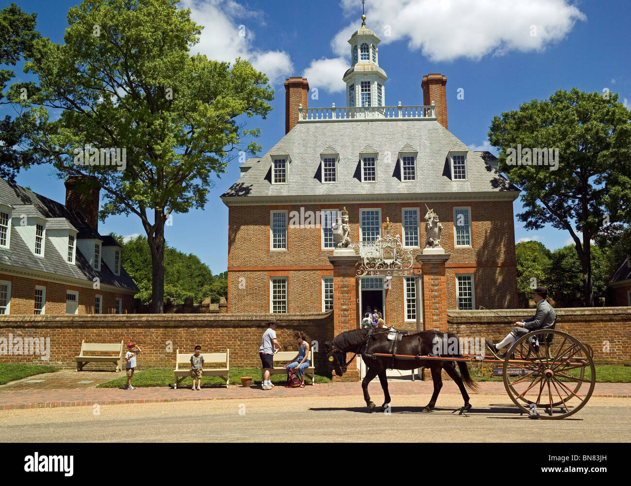 A horse-drawn cart passes the imposing Governor's Palace that dates to 1722 and can be visited in historic Colonial Williamsburg in Virginia, USA. Stock Photo