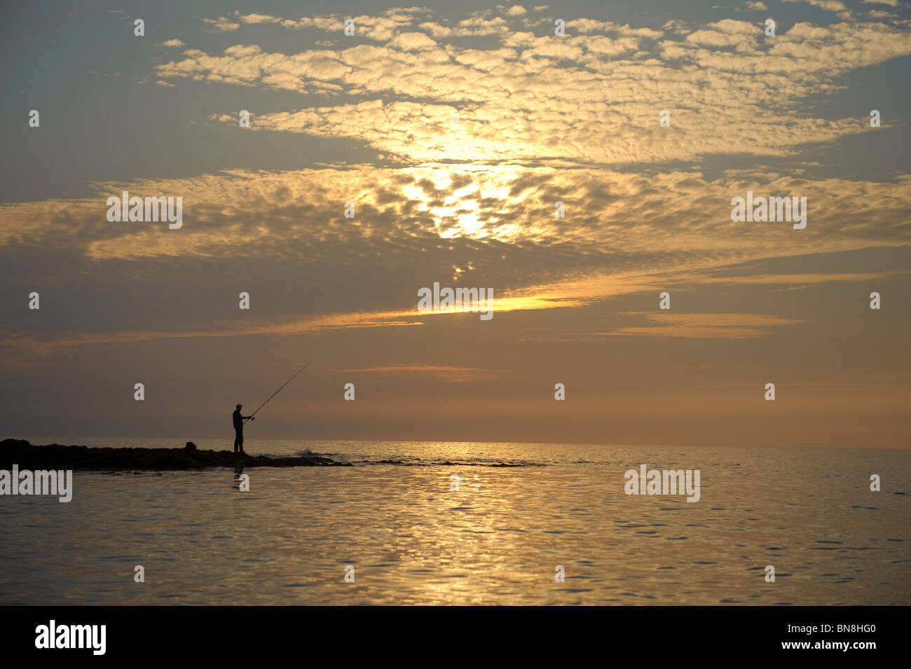 Silhouette of a man fishing in the sea at sunset, Aberystwyth Cardigan Bay west wales uk Stock Photo