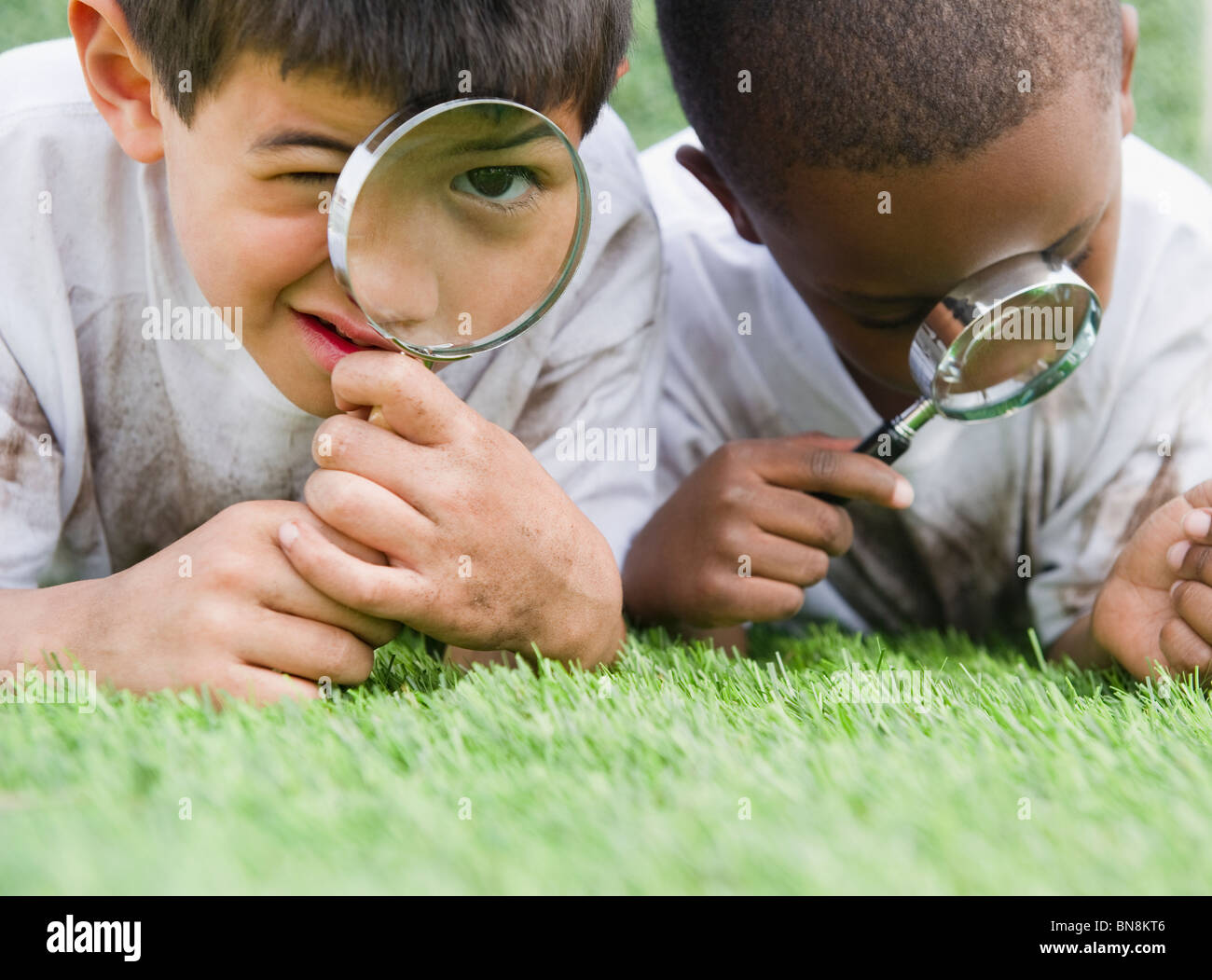Boys looking at grass through magnifying glasses Stock Photo