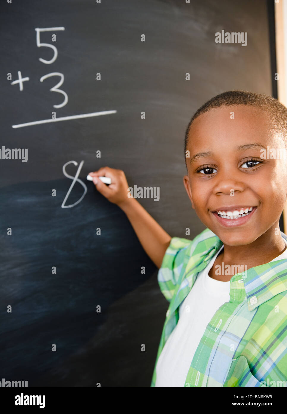 Black boy solving math problems on blackboard Stock Photo
