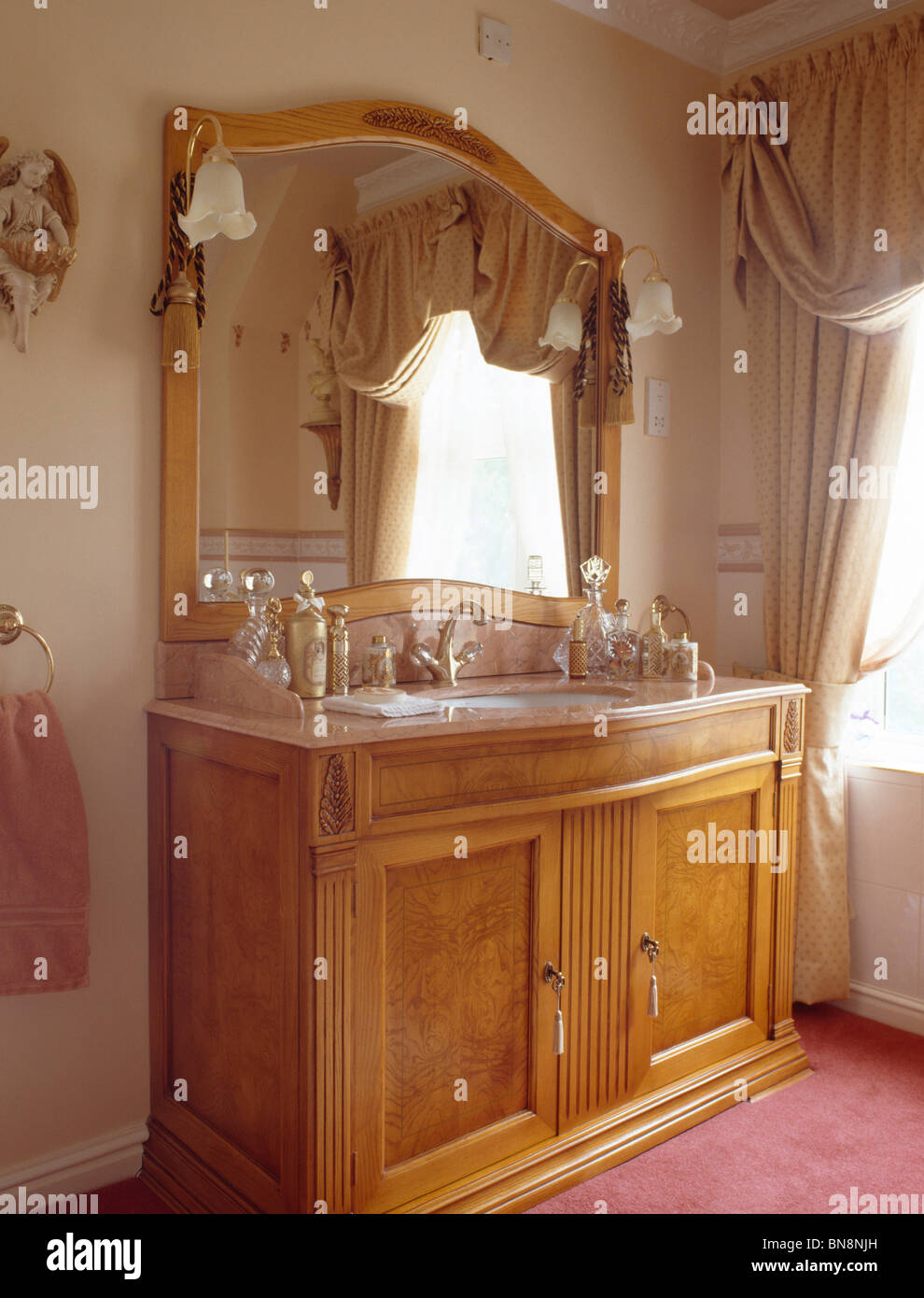 Large mirror above pale wood vanity unit in traditional bathroom Stock ...