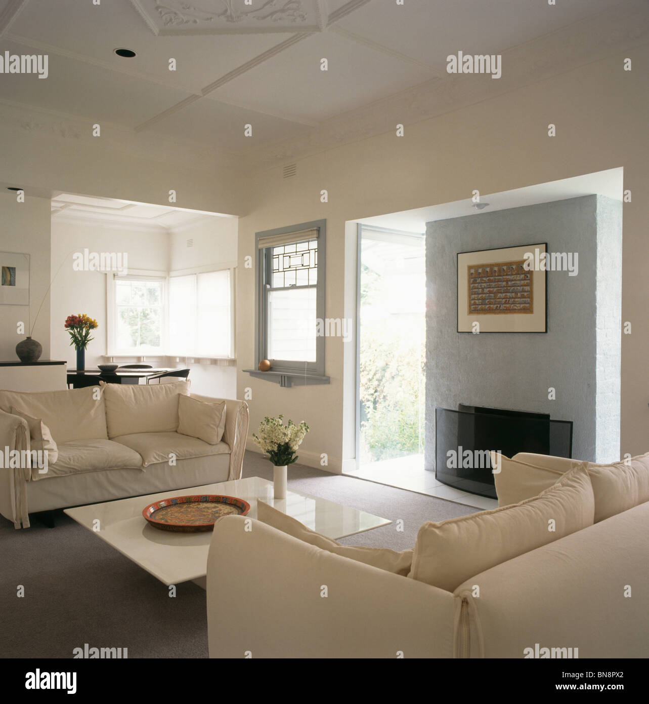 White sofas in modern white openplan living room with pale gray wall