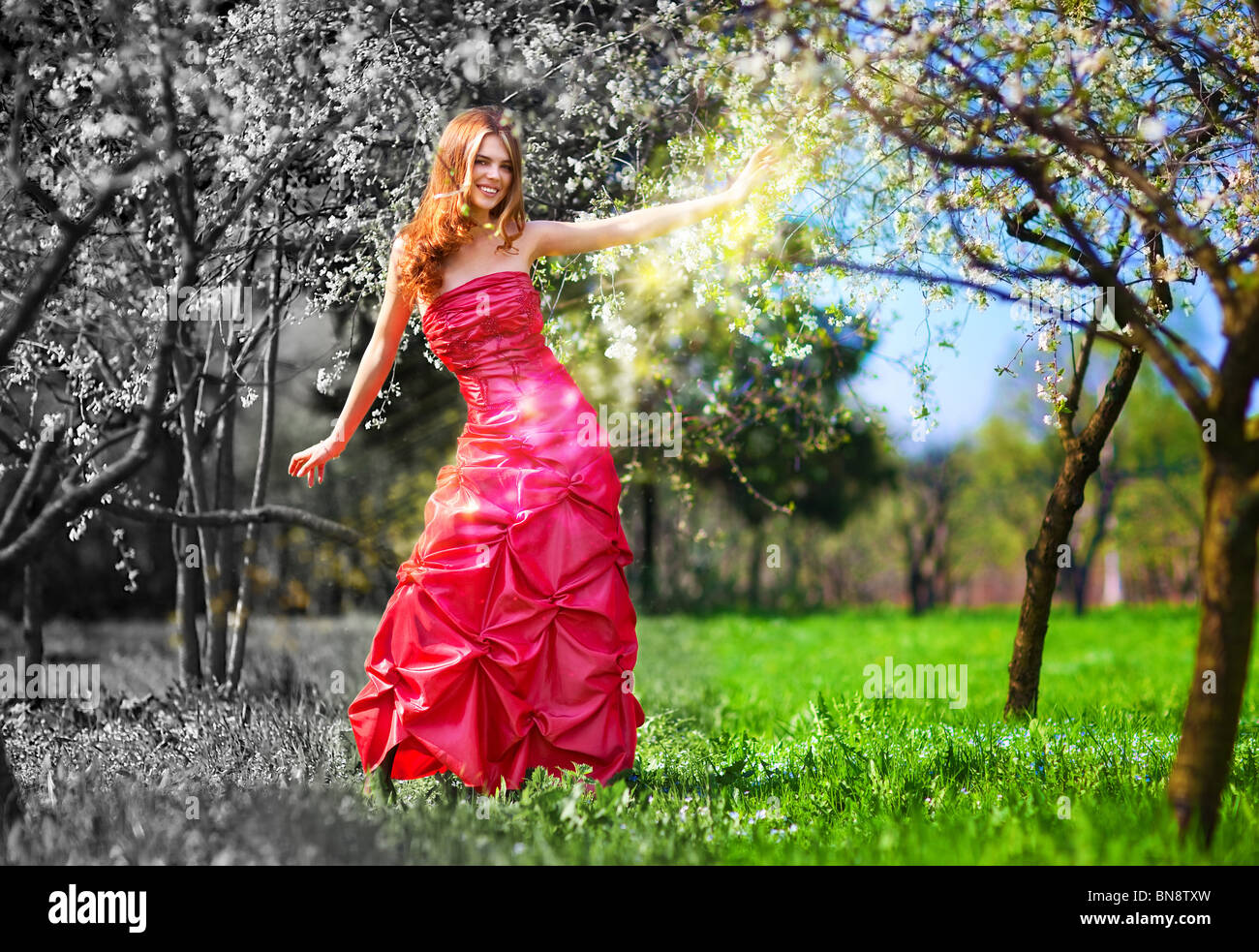 Young fairy woman in red dress painting garden. Stock Photo