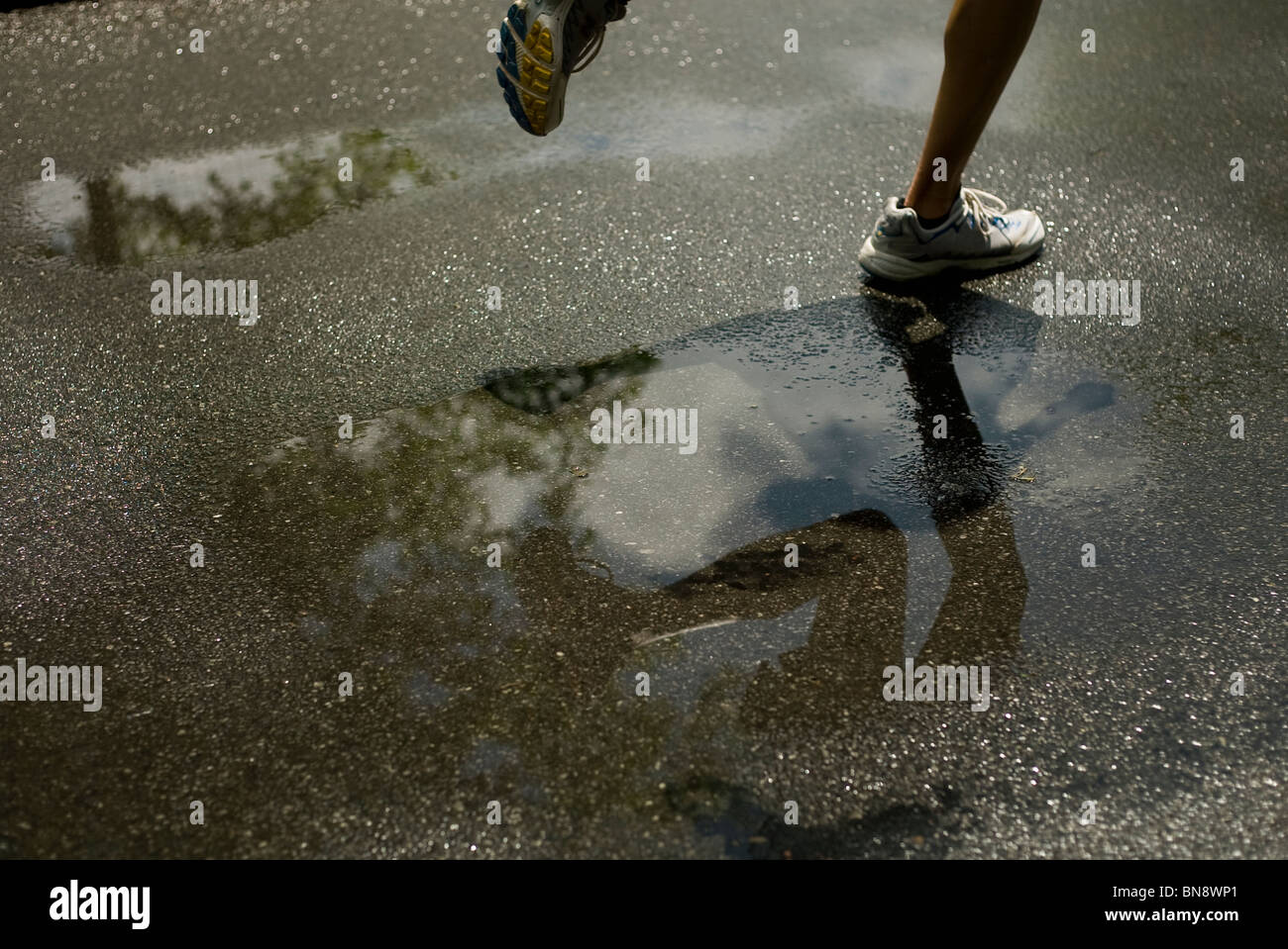 Woman running through puddle Stock Photo