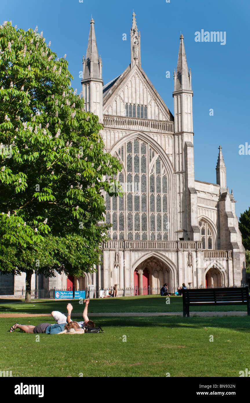 Winchester Cathedral in summer with couple relaxing on the grass nearby Stock Photo