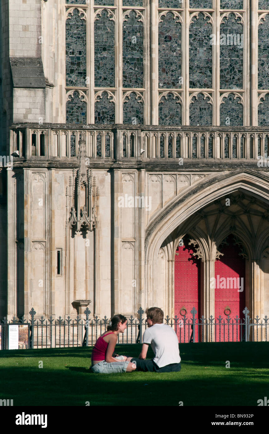 Winchester Cathedral in summer with couple relaxing on the grass nearby Stock Photo