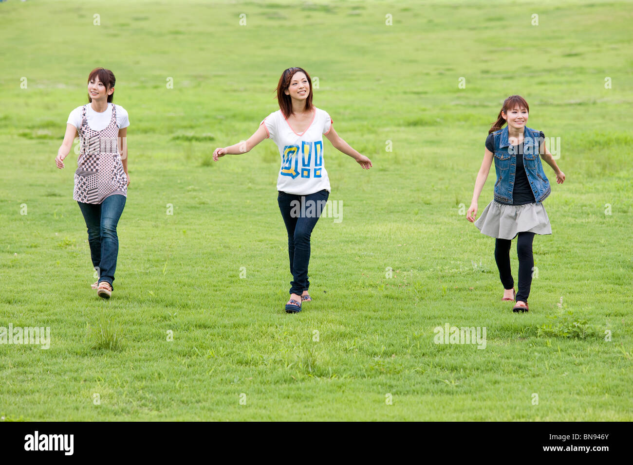 Three Young Women Walking in Green Field Stock Photo - Alamy